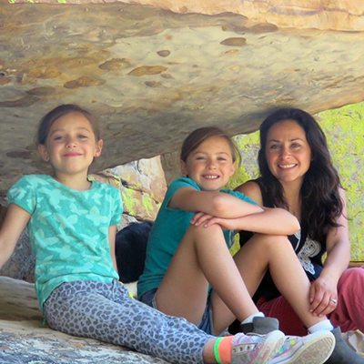An image of Jacelyn Downey Posing with her children under a rock ledge.